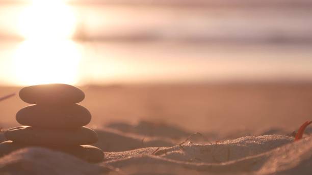 istock Stack of pebble stones, sandy ocean beach, sunset sky. Rock balancing by water. 1386834640