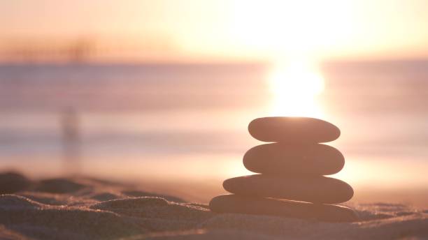 istock Stack of pebble stones, sandy ocean beach, sunset sky. Rock balancing by water. 1386835255