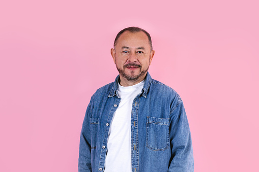 portrait of hispanic senior man wearing casual clothes smiling at camera on pink background in Mexico Latin America