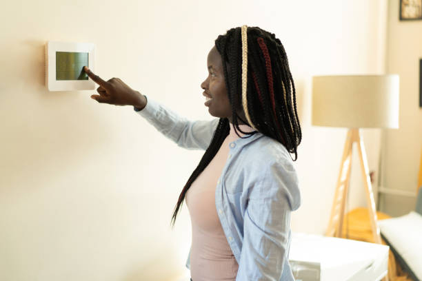 istock A woman is adjusting the temperature control on her wall 1386842058