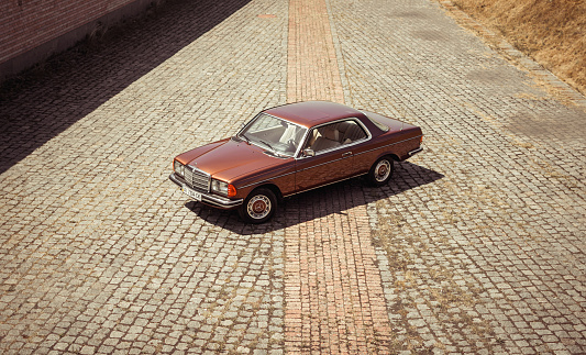 Kyiv region, Ukraine - July 18 2015: Brown classic Mercedes-Benz W123 coupe from 1970s. Three quarter view from above of brown old car