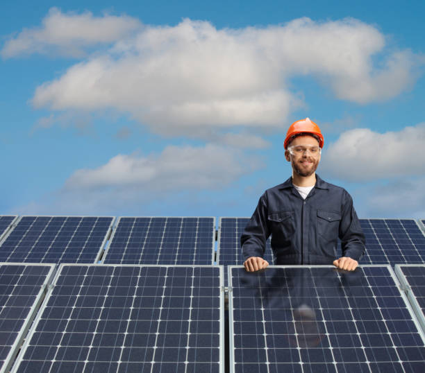 istock Male technician in a uniform posing behind solar cells 1386844034