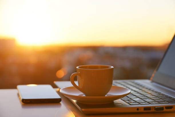 istock Coffee or tea cup on laptop and smartphone against the window with sunlight 1386844548