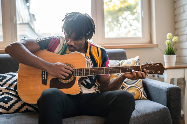 istock A man playing his guitar at home 1386844598