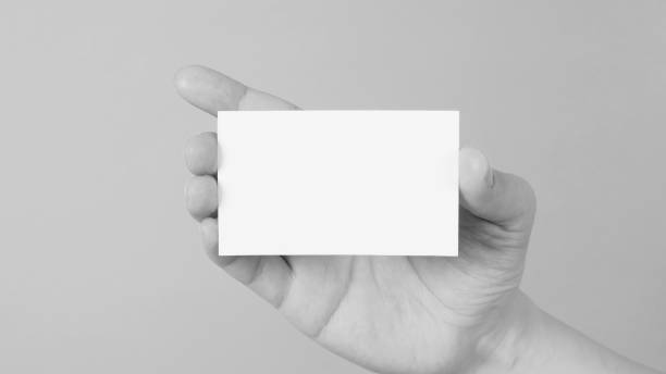 istock Empty space for text.Male hand holding white blank card isolated on mint green or Tiffany Blue background. black and white picture. 1386848114
