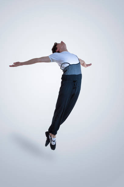 istock Professional Caucasian Male Ballet Dance Performing in Flight With Hands Outspread in Studio Against White Background. 1386848826