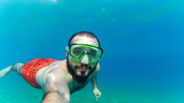 A young brunette man posing immersed in the sea