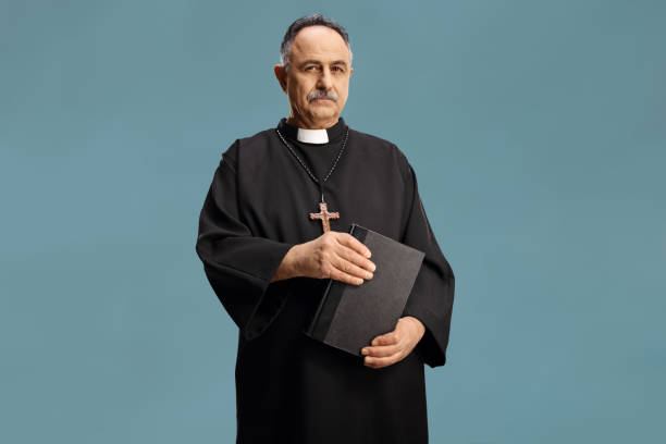istock Mature priest holding a bible and looking at camera 1386849644
