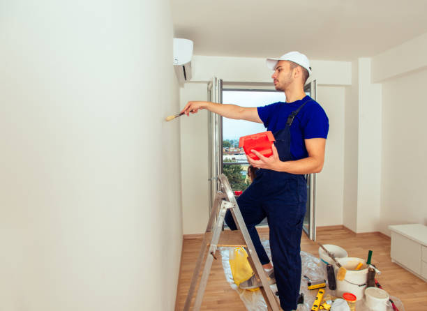 istock Young Painter In Blue Uniform Painting With Paintbrush On Wall 1386850680