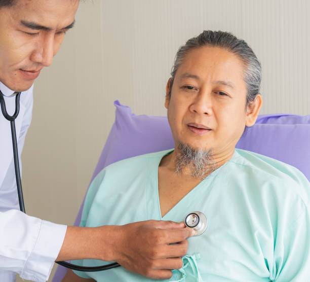 istock Face of elderly patient man unhappy, suffer, sadness from sick looking forward and doctor using stethoscope on heart. Doctor or nurse take care senior patient health admission at hospital 1386851333