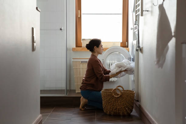istock Young indian ethnic woman folding laundry in washing machine. 1386851398