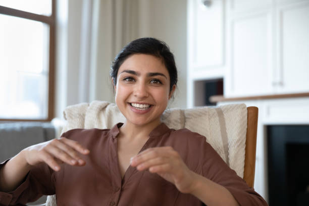 Happy millennial indian woman talking looking at camera. Happy millennial indian woman talking looking at camera, holding web camera video call conversation with friends, sitting in comfortable armchair. Smiling beautiful female blogger recording video. divergent movie review stock pictures, royalty-free photos & images