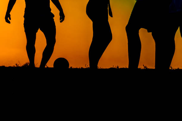 Young man is practicing Football under a big tree in the sunset. Silhouette style.