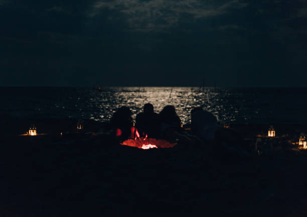 istock Buddies by campfire relaxing in the night while watching the lake 1386852520