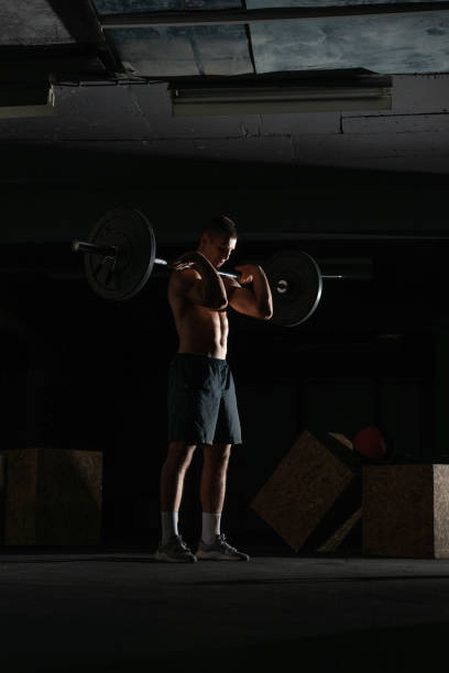 istock Silhouette of a fit strong shirtless athlete doing squats. Weight lifting workout concept. 1386855430