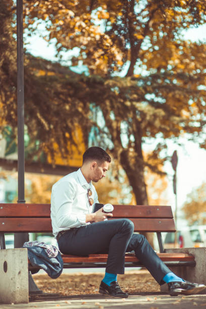 istock Stylish businessman sitting in the park 1386855825