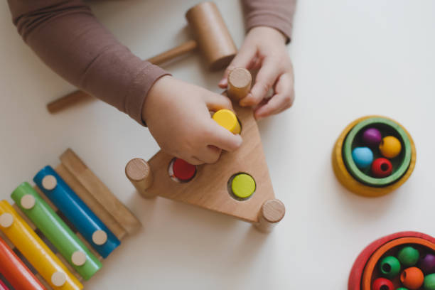 draufsicht kinderhände spielen und bauen mit bunten holzspielzeugen auf weißem holztisch. frühes lernen und entwicklung - cube baby child block stock-fotos und bilder