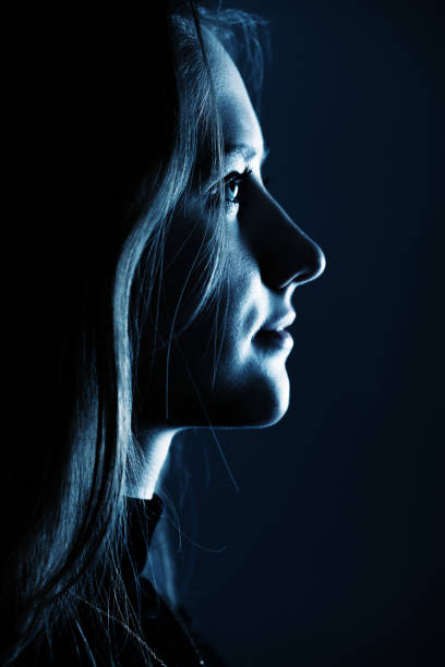 istock Low light side view of woman studio portrait 1386857633