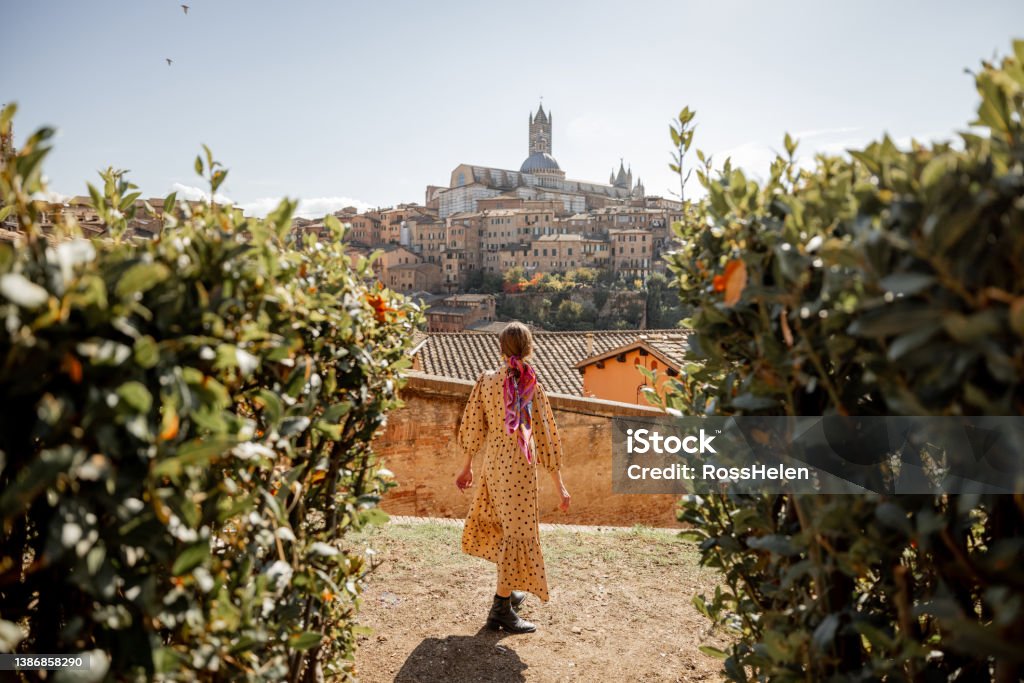 woman walks on background of cityscape of Siena old town in Italy Stylish woman walks on background of cityscape of Siena old town. Concept of travel famous cities in Tosacny region of Italy Tuscany Stock Photo