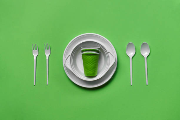 istock Colorful plastic disposable tableware on green background with copy space. The concept of picnic utensil. Top view. Selective focus. Close-up 1386859793
