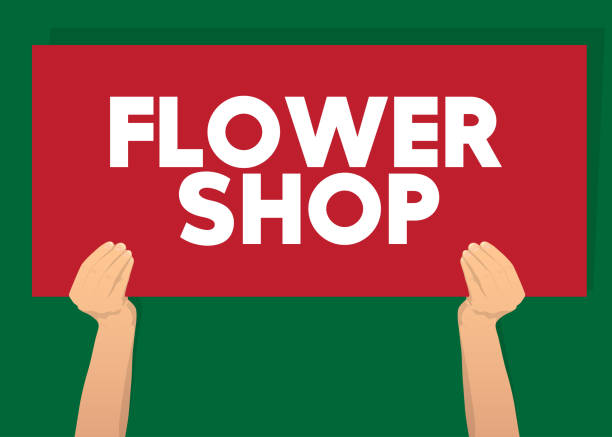 istock Hand holding banner with Flower Shop text on paper. 1386859873