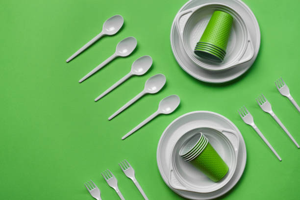 istock Colorful plastic disposable tableware on green background with copy space. The concept of picnic utensil. Top view. Selective focus. Close-up 1386860027
