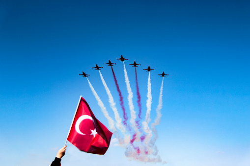 Antalya, Turkey - April 23, 2017: Turkish Jets demonstrating in the skies of Antalya to celebrate the Republic Day and a person who has raised the Turkish Flag to the air.