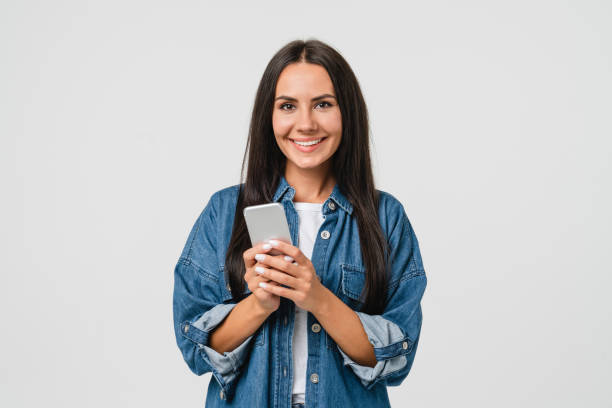 giovane ragazza caucasica sorridente che utilizza il cellulare dello smartphone per l'e-learning, l'e-commerce, l'e-banking online, le applicazioni mobili, facendo scommesse nel casinò isolato su sfondo bianco - latin american and hispanic ethnicity isolated on white happiness cheerful foto e immagini stock