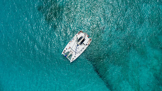 Beautiful sailing catamaran at anchor. Aerial view of a yacht in clear turquoise water in the Indian Ocean. Yachting and travel concept