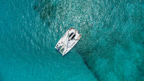 Beautiful sailing catamaran at anchor Beautiful sailing catamaran at anchor. Aerial view of a yacht in clear turquoise water in the Indian Ocean. Yachting and travel concept catamaran sailing boats stock pictures, royalty-free photos & images