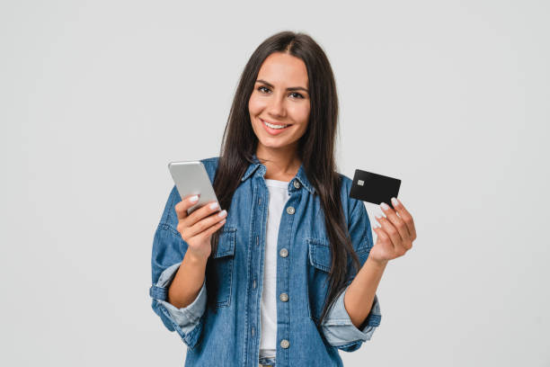 istock Happy caucasian young woman mobile user bank client customer holding credit card while using mobile e-banking e-commerce application for online shopping, payments, transactions, cashback 1386863885