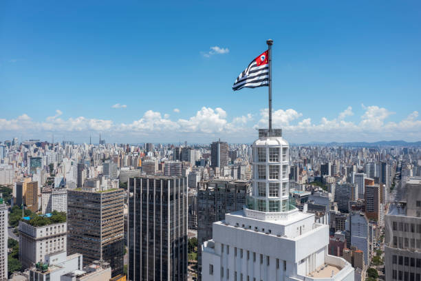 Sao Paulo state flag fluttering at the top of the Santander lighthouse, city in the background, blue sky stock photo
