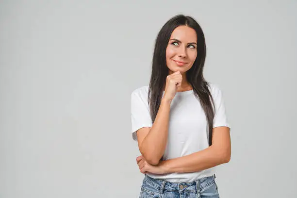 Dreamy pensive thoughtful caucasian young woman girl student freelancer thinking about startup, creating new ideas isolated in grey background