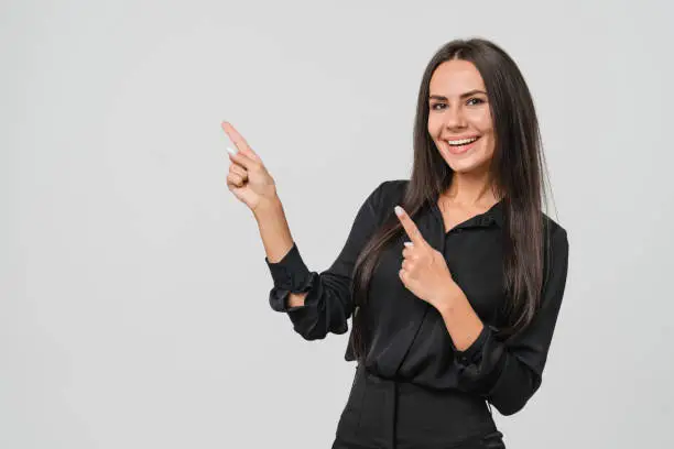 Photo of Confident caucasian young businesswoman freelancer CEO boss manager bank employee in formal wear looking at camera pointing at free copy space isolated in white background