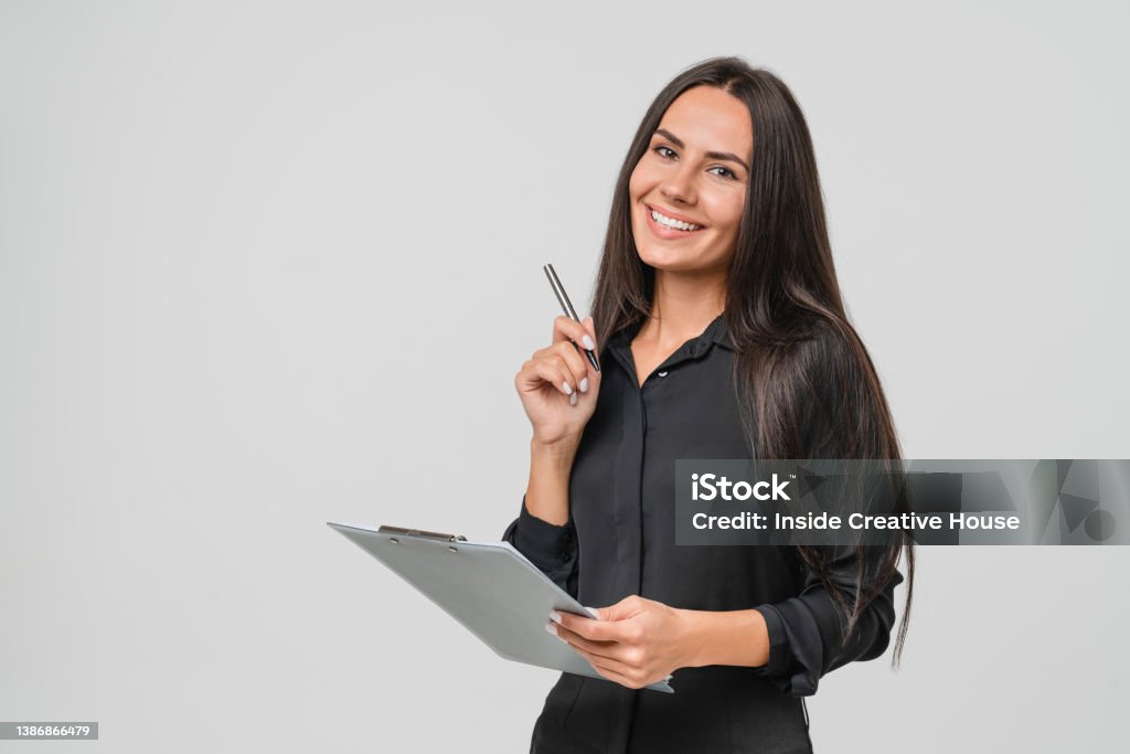 Smiling confident caucasian young businesswoman auditor writing on clipboard, signing contract document isolated in white background One Woman Only Stock Photo