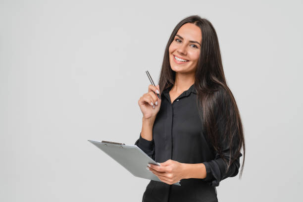 Smiling confident caucasian young businesswoman auditor writing on clipboard, signing contract document isolated in white background stock photo