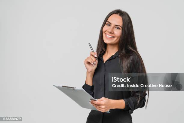 Smiling Confident Caucasian Young Businesswoman Auditor Writing On Clipboard Signing Contract Document Isolated In White Background Stock Photo - Download Image Now