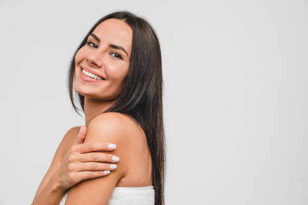 Happy healthy beautiful caucasian young woman in spa bath towel hugging embracing herself looking at camera isolated in white background. Beauty treatment and care stock photo