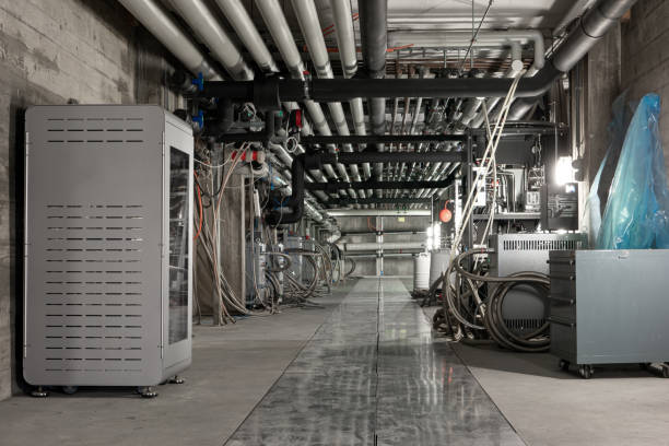 istock Ceiling mounted industrial pipelines and science laboratory machinery inside underground building, Long corridor with metal floors, dimly lit, no people 1386867817