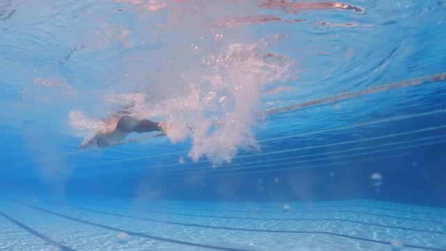 underwater low angle view Asian chinese male swimmer swimming with butterfly style in swimming pool
