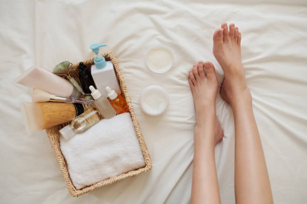 Skincare Products on Bed Feet of young woman on bed next to basket of skincare products like cream, lotions and oils foot spa treatment stock pictures, royalty-free photos & images