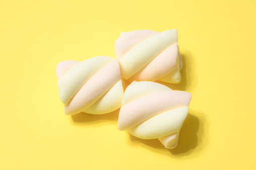 swirled marshmallows on yellow background, close-up