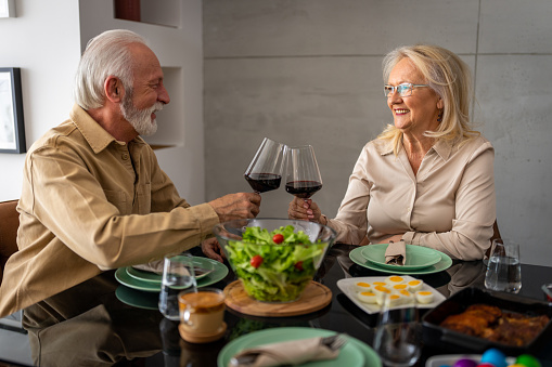 Happy senior couple eating together for Easter and enjoying wine