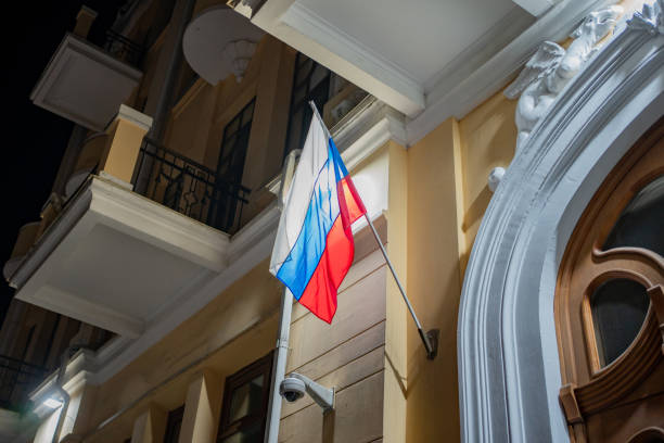 istock flag of Russian Federation develops in wind at night on administrative building. 1386875713