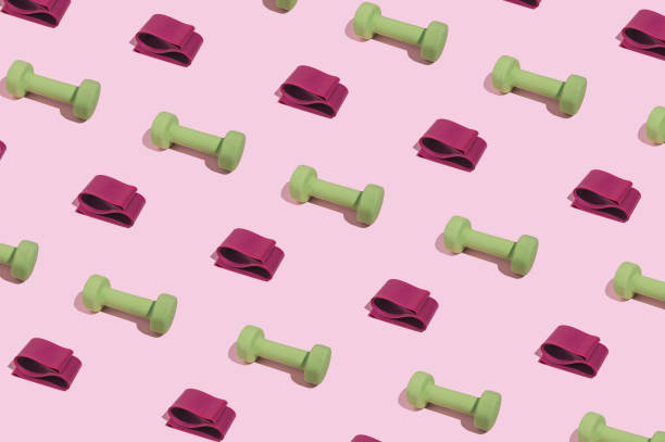 istock Modern minimal pattern with green dumbbells and elastic booty bands on bright pink background. Trendy female fitness aesthetic. 1386875791
