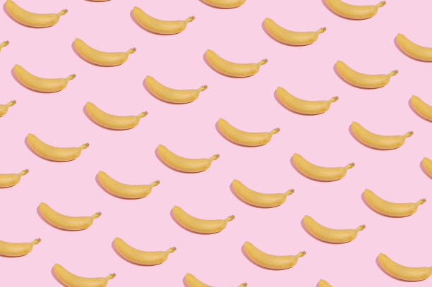 istock Modern minimal pattern with yellow bananas on bright pink background. Trendy summer fruit aesthetic. 1386875818