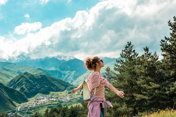 ragazza femmina felice sorridente gioiosa con le braccia alzate danzando sul campo con il cielo blu sul paesaggio - arms raised green jumping hand raised foto e immagini stock