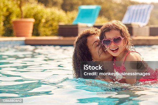 istock Laughing Mother And Daughter Wearing Sunglasses Having Fun In Swimming Pool On Summer Vacation 1386880642