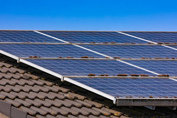 Dirty photovoltaic system with energy-producing solar panels mounted on the roof of a private house stock photo