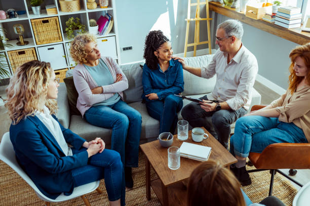 istock Mental health counselor talking with people during a group therapy session 1386881460